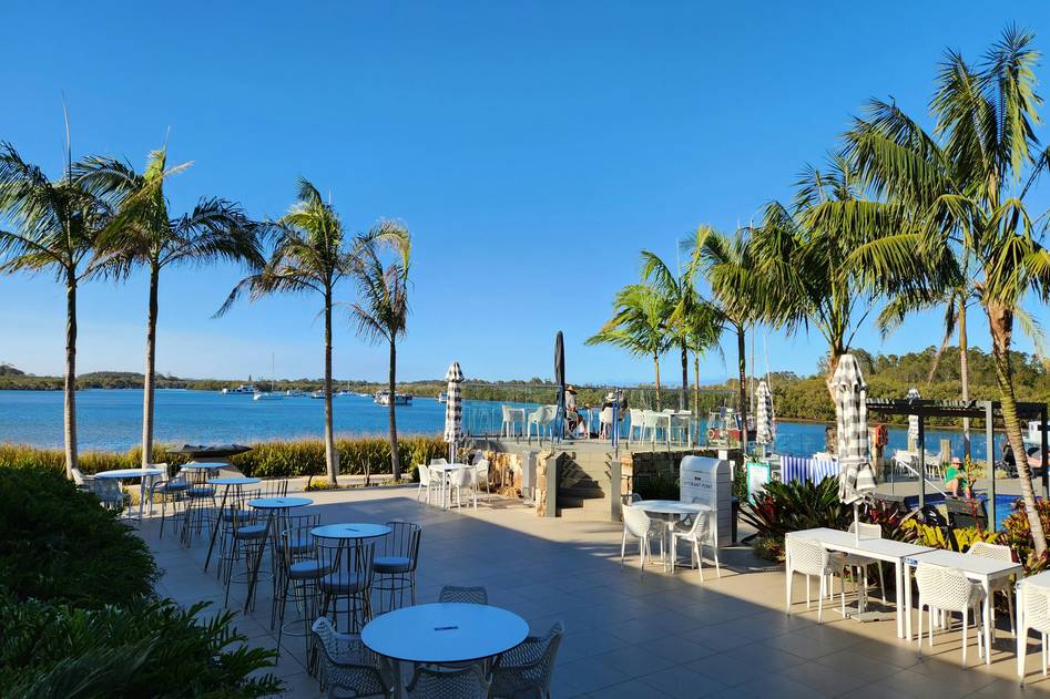 Editor setting up a large cantilever beach umbrella on a sunny coastline