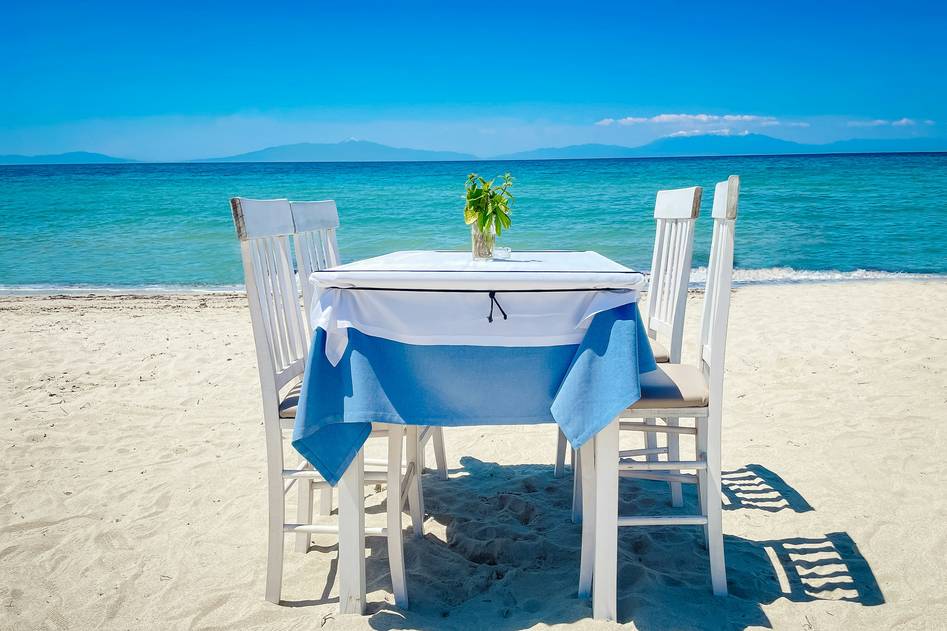 Stylish blue and white striped beach umbrella casting shade on sandy shore with ocean in background