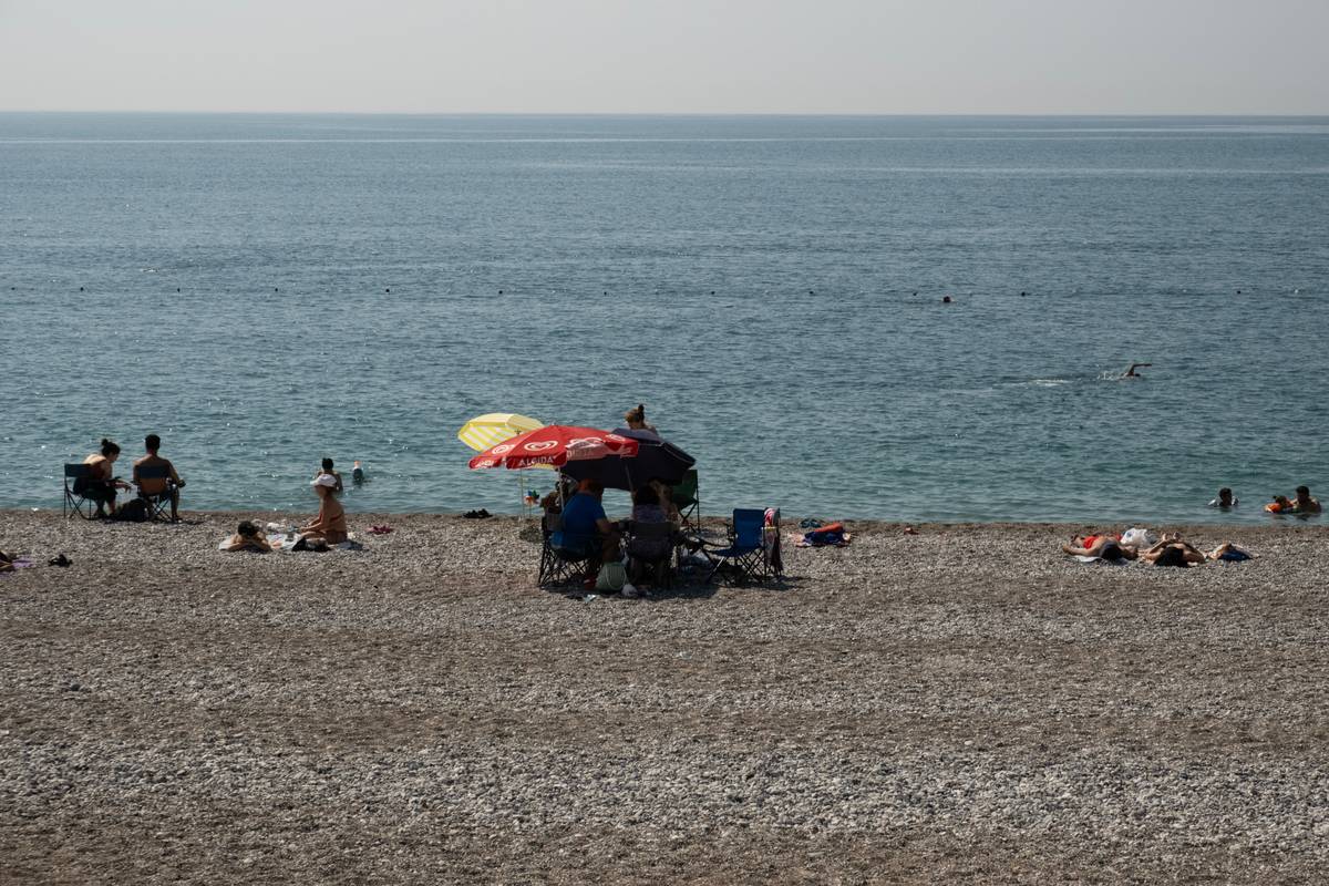 shade umbrella with base secured on sandy beach with weighted stand and tilt mechanism