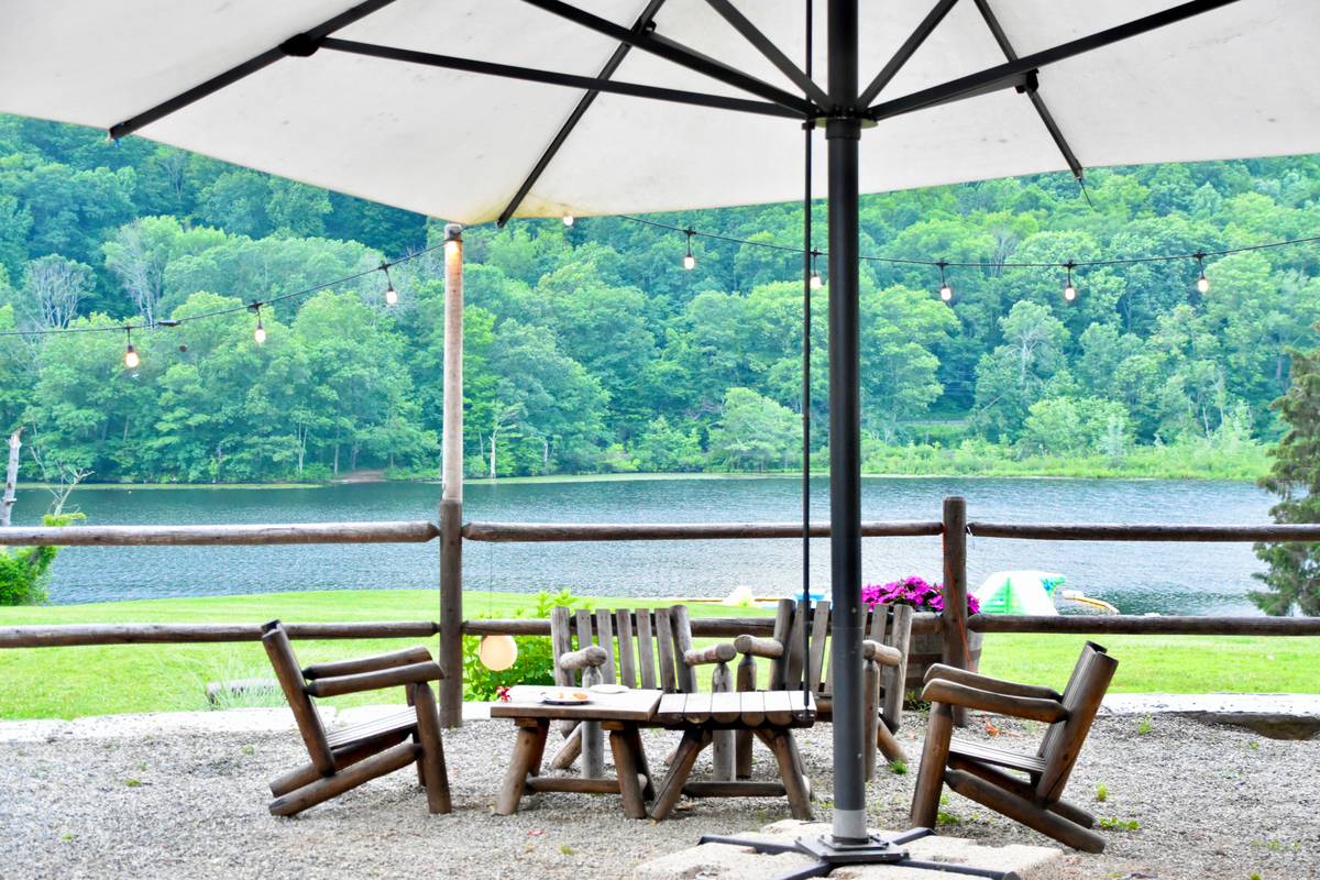 sunbrella umbrella for patio with navy blue canopy open over teak table and chairs on a sunny deck